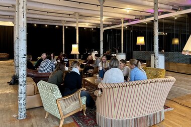 In gemütlicher Atmosphäre sitzen Workshop-Teilnehmende auf Upcycling-Möbeln und diskutieren in Kleingruppen – eine informelle und kreative Arbeitssituation. | © Holger Sigmund