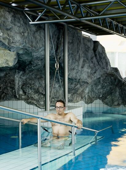 Ein Mann im Rollstuhl befindet sich im Wasser des Hallenbads im Hotel Val Blu. | © Val Blu