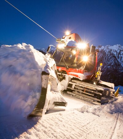 Der Kässbohrer mit Winde hängt am Windenseil und schiebt Schnee im Schild nach oben. | © Bergbahnen Brandnertal, Michael Marte