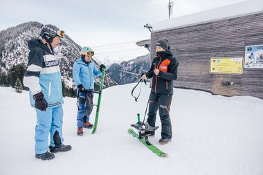 Mitarbeiter erklärt Gästen das Sportgerät Snooc. | © Bergbahnen Brandnertal, Timo Hummel