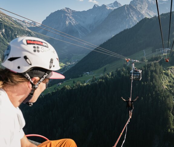 Ein Slackliner wagt den Weltrekordversuch und wandert auf der dünnen Line von Gondel zu Gondel bei der Panoramabahn. | © Michael Kreyer