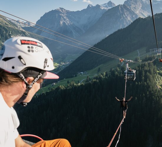 Ein Slackliner wagt den Weltrekordversuch und wandert auf der dünnen Line von Gondel zu Gondel bei der Panoramabahn. | © Michael Kreyer
